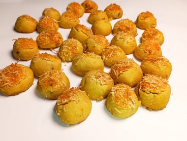 Beyaz arka planda peynir parçacıkları serpiştirilmiş bir avuç ananaslı kek.