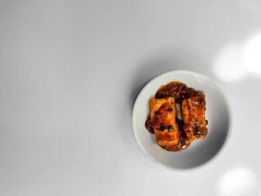 İzole edilmiş beyaz üzerine baharatlı biberli bir tabak kızarmış tofu.