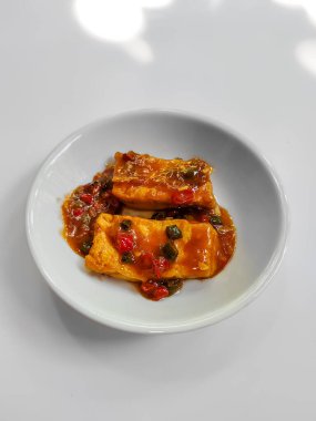 İzole edilmiş beyaz üzerine baharatlı biberli bir tabak kızarmış tofu.