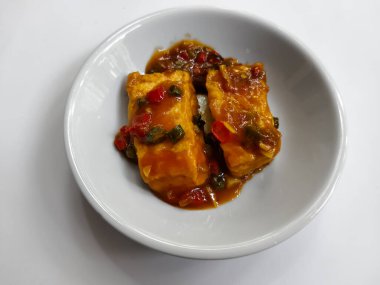 İzole edilmiş beyaz üzerine baharatlı biberli bir tabak kızarmış tofu.