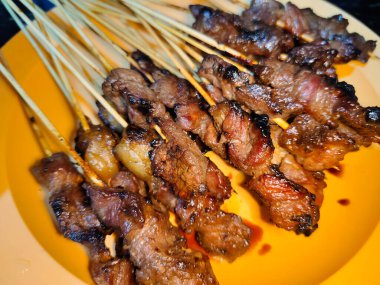 Bir sürü sığır şişini bir tabakta bir sürü et şişi ile kapatıyoruz.