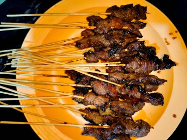 Bir sürü sığır şişini bir tabakta bir sürü et şişi ile kapatıyoruz.