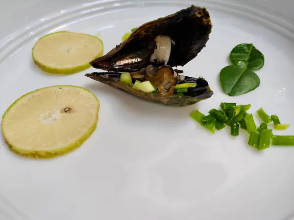 dilimlenmiş limon ve sebzeli bir tabak deniz tarağı.