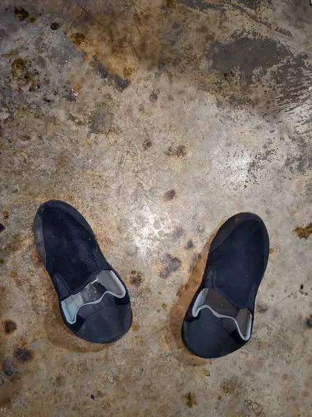 Eski bir çift yıpranmış ayakkabı eski ve kirli bir zeminde