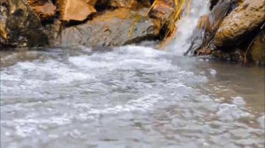 Su küçük bir nehirde kayaların arasından akıyor.