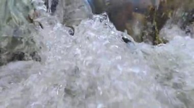 Su küçük bir nehirde kayaların üzerinden akıyor.