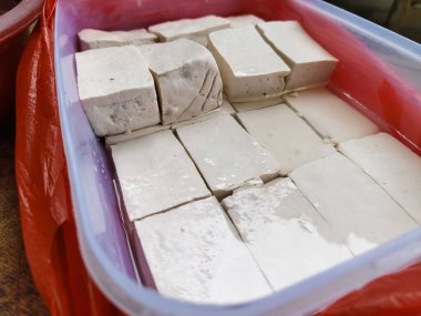 Plastik bir kapta suyla doldurulmuş bir avuç çiğ tofu parçasına yakın çekim yapın.