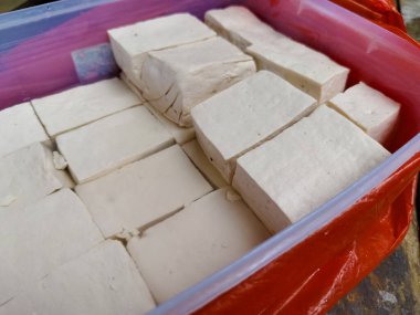 Plastik bir kapta suyla doldurulmuş bir avuç çiğ tofu parçasına yakın çekim yapın.