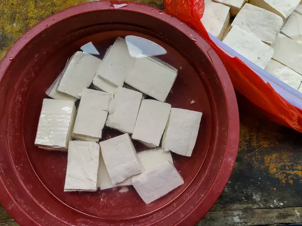 Plastik bir kapta suyla doldurulmuş bir avuç çiğ tofu parçasına yakın çekim yapın.
