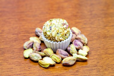 Tahta bir masanın tepesinde fıstıklı Brigadeiro var.