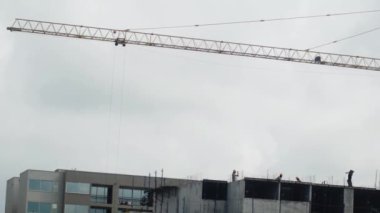 İnşaat işçilerinin inşaat sahasında yüksek bir vinç etrafında yaptıkları dinamik bir sahne. Bu resim, kentsel gelişim ve altyapı projeleri için gerekli takım çalışması ve makineleri yakalar