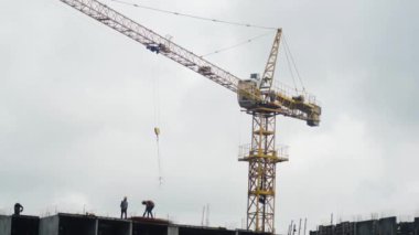 İnşaat işçilerinin inşaat sahasında yüksek bir vinç etrafında yaptıkları dinamik bir sahne. Bu resim, kentsel gelişim ve altyapı projeleri için gerekli takım çalışması ve makineleri yakalar