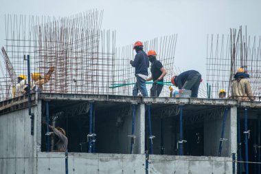 inşaat işçileri aktif olarak modern bir apartman bloğu inşa ediyorlar, şehir inşaatında takım çalışması ve beceri sergiliyorlar. Bu resim gelişim ve işçilik süreçlerini vurgular