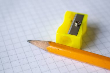 Yaratıcılığı, yazmayı ve organizasyonu temsil eden beyaz bir şebeke kağıdına düzgünce yerleştirilmiş bir kalem ve keskinleştirici. Bu resim eğitim, kırtasiye ve ofis malzemeleri ile ilgili projeler için idealdir.