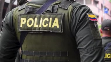 Arkadan yürüyen bir polis memuru, üniformalı Kolombiya polisi, geçit törenindeki kolluk kuvvetlerinin arka görüntüsü. Yüksek kaliteli FullHD görüntüler