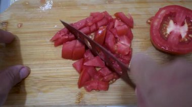 Domatesleri kesme tahtasında doğrama, taze domatesleri bıçakla dilimleme, domatesleri pişirmeye hazırlama. Yüksek kalite 4k görüntü