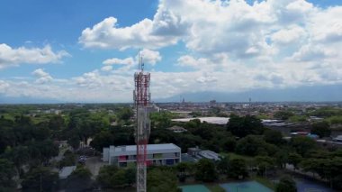 5G iletişim kulesinin kırsal alan üzerindeki hava aracı görüntüsü, 5G anten kulesinin insansız hava aracı görüntüleri, yeşilliklerle çevrili 5G baz istasyonunun yüksek çözünürlüklü hava görüntüsü. Yüksek