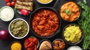 Yağ tavuğu, saag paneer, naan ekmeği ve pirinç gibi çeşitli lezzetli Hint yemeklerini gösteren canlı bir genel çekim..