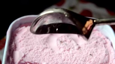 Pembe çilekli dondurmanın içinde metal bir dondurma kepçesinin yakın plan çekimi..