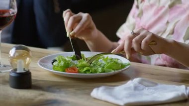 Romantik bir akşam yemeğinde taze yeşil salataya baharat katan bir kadının ellerini yakından çek..