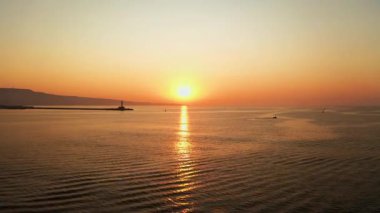 Altın ışığa karşı bir deniz feneri siluetiyle okyanusun üzerinde sersemletici bir gün doğumu..