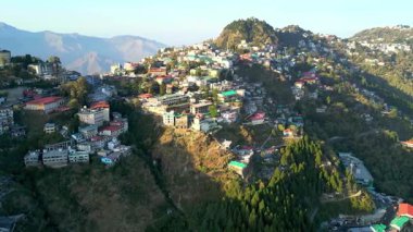 Tepedeki Yaşamın Renkli Dağ Kasabası Hava Manzarası. Çarpıcı hava görüntüleri, Mussoorie ya da Shimla gibi Hindistan 'ın kuzey bölgelerindeki yemyeşil dağların arasında yuva yapmış canlı bir tepe kenti yakalar. Renkli evler yapışıyor