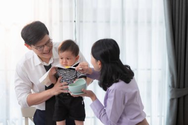 Baba ve anne, işe gitmeden önce oğullarına kahvaltı yedirirler.