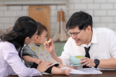 Baba ve anne, işe gitmeden önce oğullarına kahvaltı yedirirler.