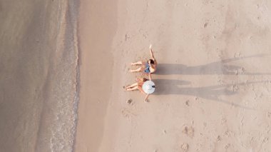 Sahilde dinlenen bir ailenin üst görüntüsü.