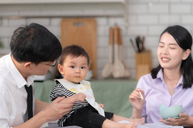 Baba ve anne, işe gitmeden önce oğullarına kahvaltı yedirirler.