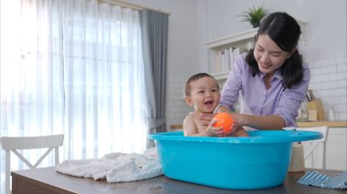 Anne bebeğe banyo yaptırdığında, o bundan zevk alıyor.