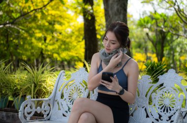 Genç bir kadın, sosyal medyaya bağlanmak ve rahatlatıcı müzik dinlemek için akıllı telefon kullanarak egzersiz yaparken ara veriyor.