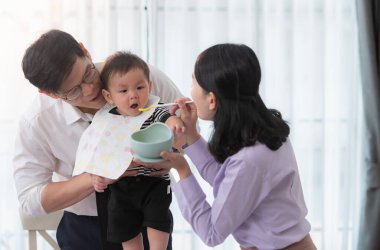 Baba ve anne, işe gitmeden önce oğullarına kahvaltı yedirirler.