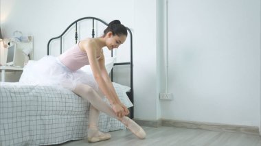 Kız bir bale öğrencisi, evde bale çalışmadan önce yatak odasında ısınıyor.