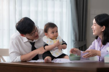 Baba ve anne, işe gitmeden önce oğullarına kahvaltı yedirirler.