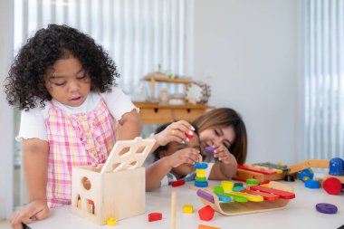 Tatilde bir kadın ve iki küçük kızı yere oturup birlikte oyuncak oynuyorlar.