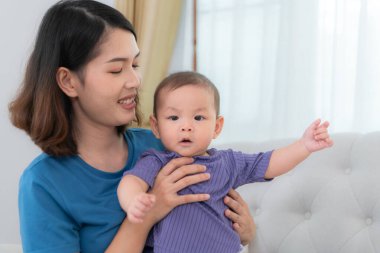 Bir anne, küçük çocuğunu evin oturma odasındaki kanepede uyuması için sakinleştirir.
