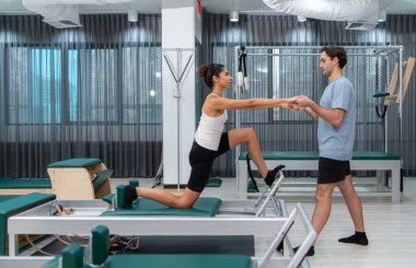 Genç bir adam ve genç bir kadın pilates egzersizleri yapıyorlar.