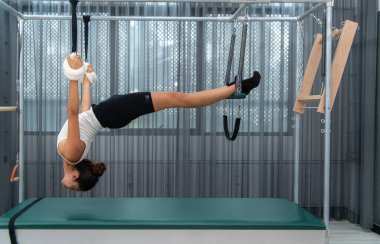 Pilates Cadillac 'ı üzerinde pilates yapan genç bir kadın.