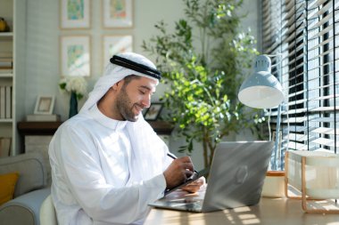 Evde dizüstü bilgisayarda çalışan genç Arap işadamının portresi