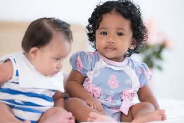 İki küçük kardeş, sıcak ve aile dolu bir yatak odasında yatakta birlikte oynuyorlar.