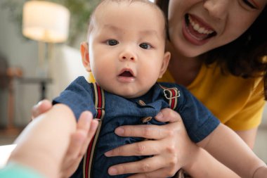 Küçük bir çocuk neşeyle oyuncaklarla oynuyor salonun zemininde annesiyle.