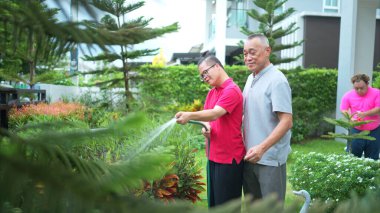 İzin günlerinde, büyükbaba ve torun evin bahçesindeki ağaçları sulamalarına yardım eder.
