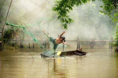 Nehirdeki bir teknede balık yakalamak için balık ağı kullanan iki çiftçi.