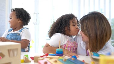 Tatilde bir kadın ve iki küçük kızı yere oturup birlikte oyuncak oynuyorlar.