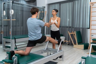 Genç bir adam ve genç bir kadın pilates egzersizleri yapıyorlar.
