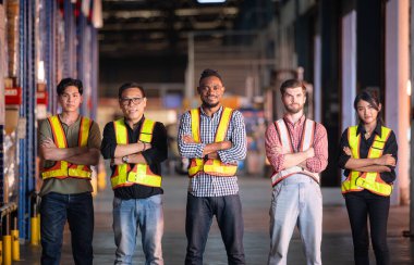 Depoda kollarını kavuşturmuş grup çalışanlarının portresi.