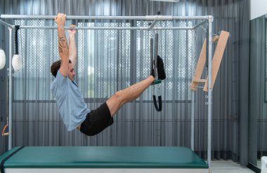 Genç bir adam pilates Cadillac 'ında pilates egzersizi yapıyor.