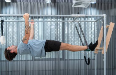 Genç bir adam pilates Cadillac 'ında pilates egzersizi yapıyor.