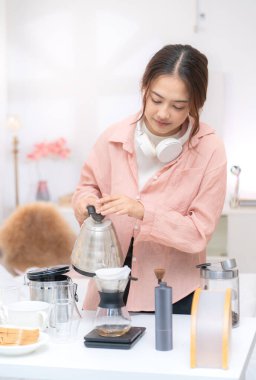 Asyalı genç bir kadın kahvaltıda ekmek ve kahve yiyor. İşten önce sabah rutini.